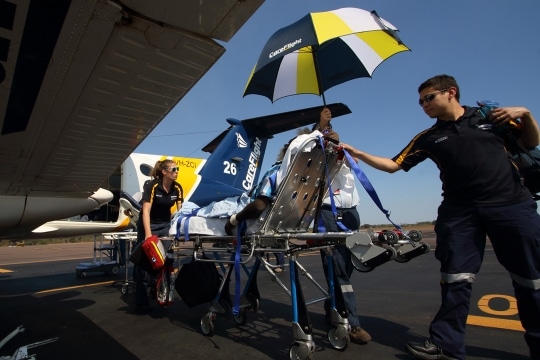 CareFlight staff transport patient on stretcher to aeroplane